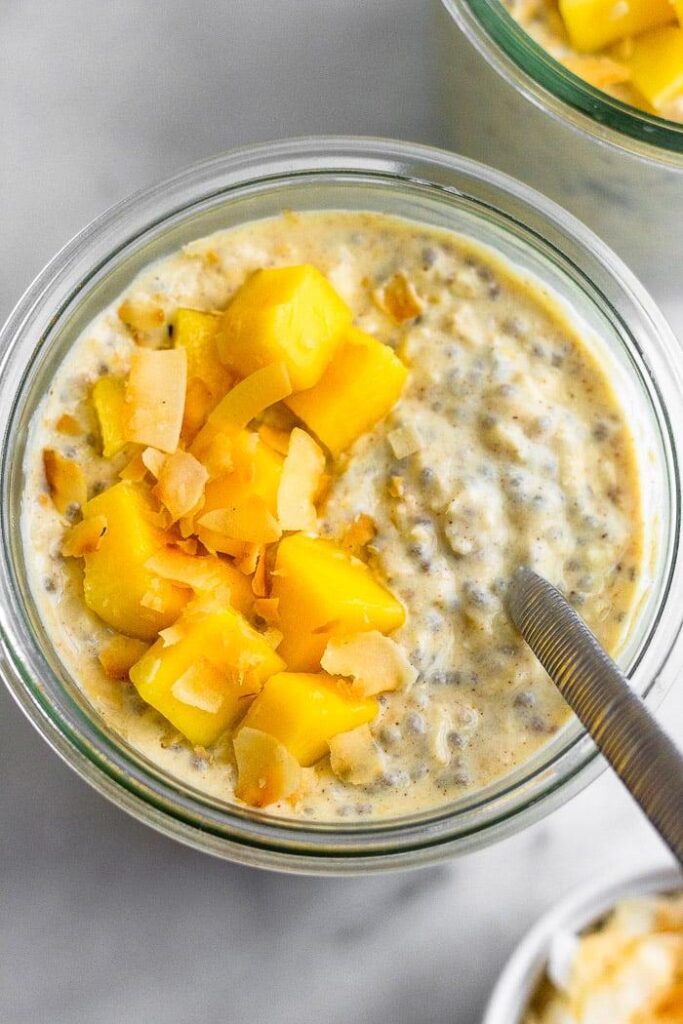 Toma aérea de un tarro lleno de saludable avena de la noche a la mañana con mango y coco.