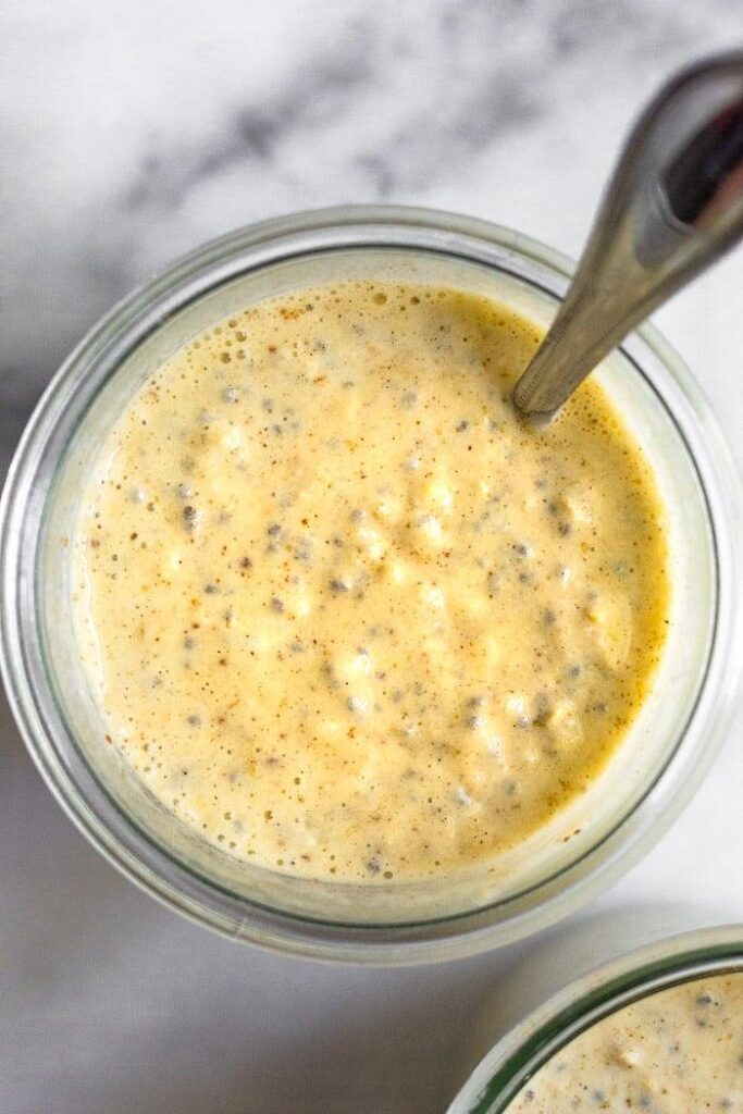 Toma aérea de una saludable avena de la noche a la mañana con yogur del que sale una cuchara.